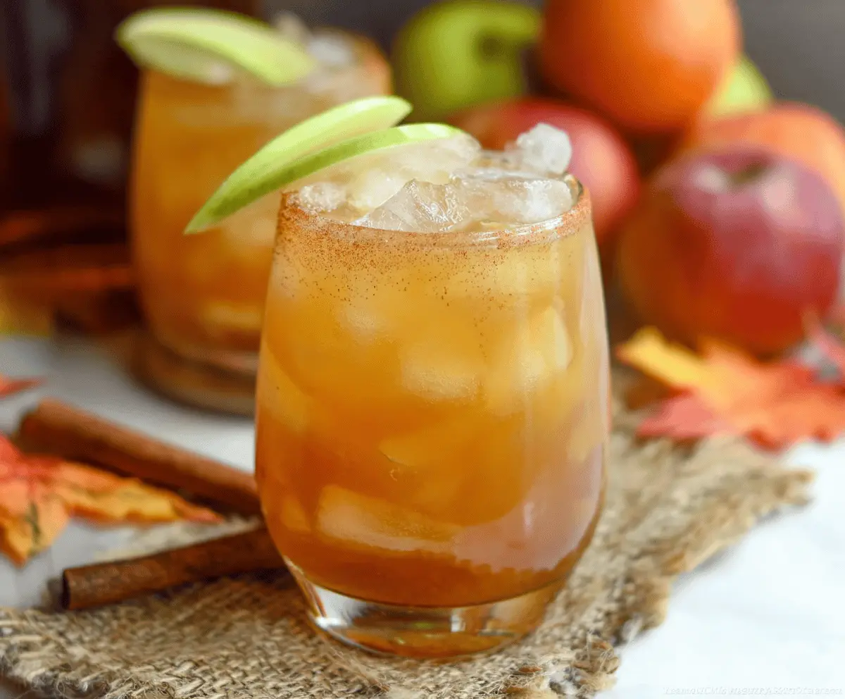 Delicious Caramel Apple Cider Bourbon Cocktail garnished with apple slices and caramel drizzle in a cocktail glass