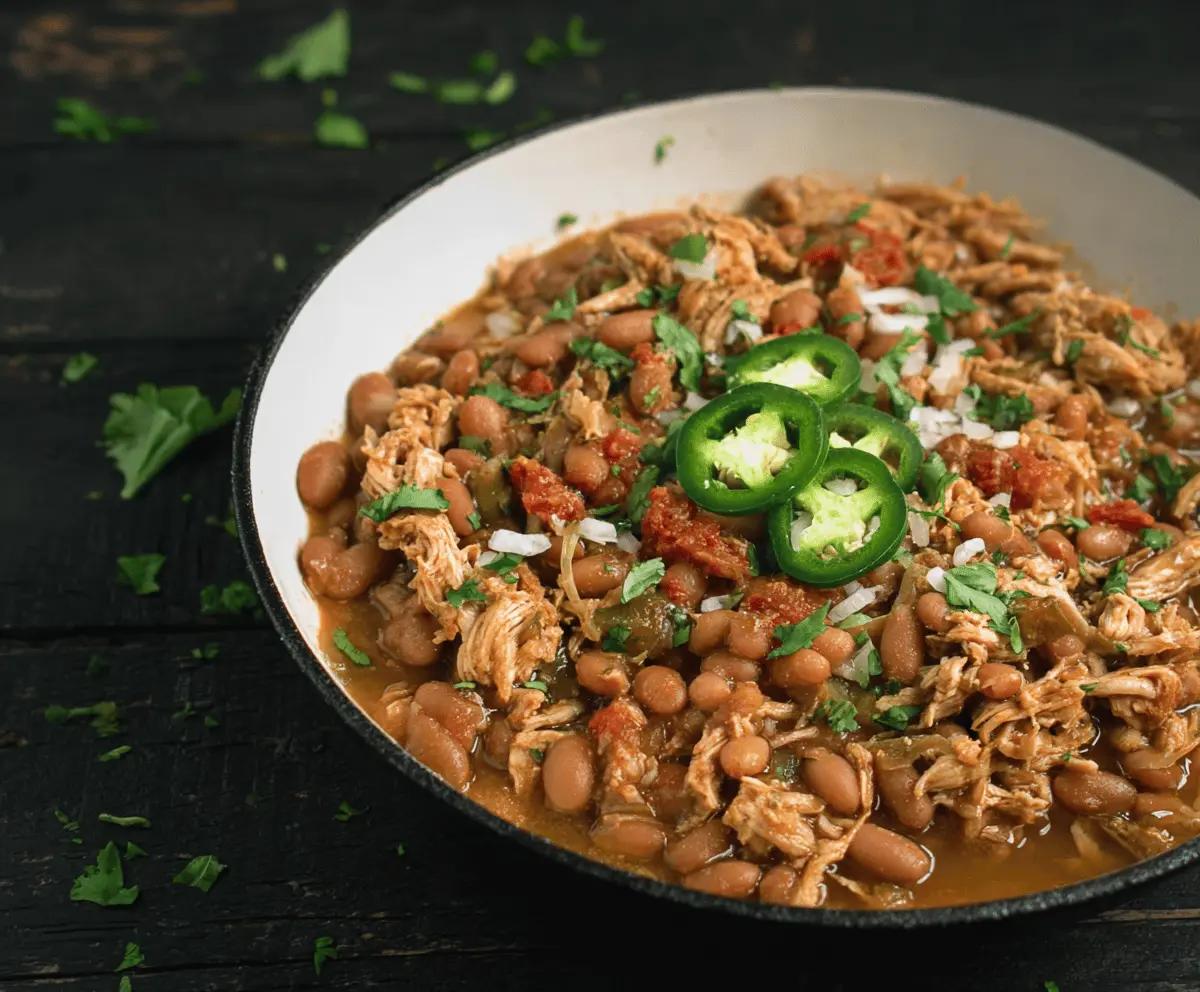 Spicy Jalapeño Beans with Tender Shredded Chicken served in a bowl, garnished with fresh herbs for a flavorful, hearty meal.