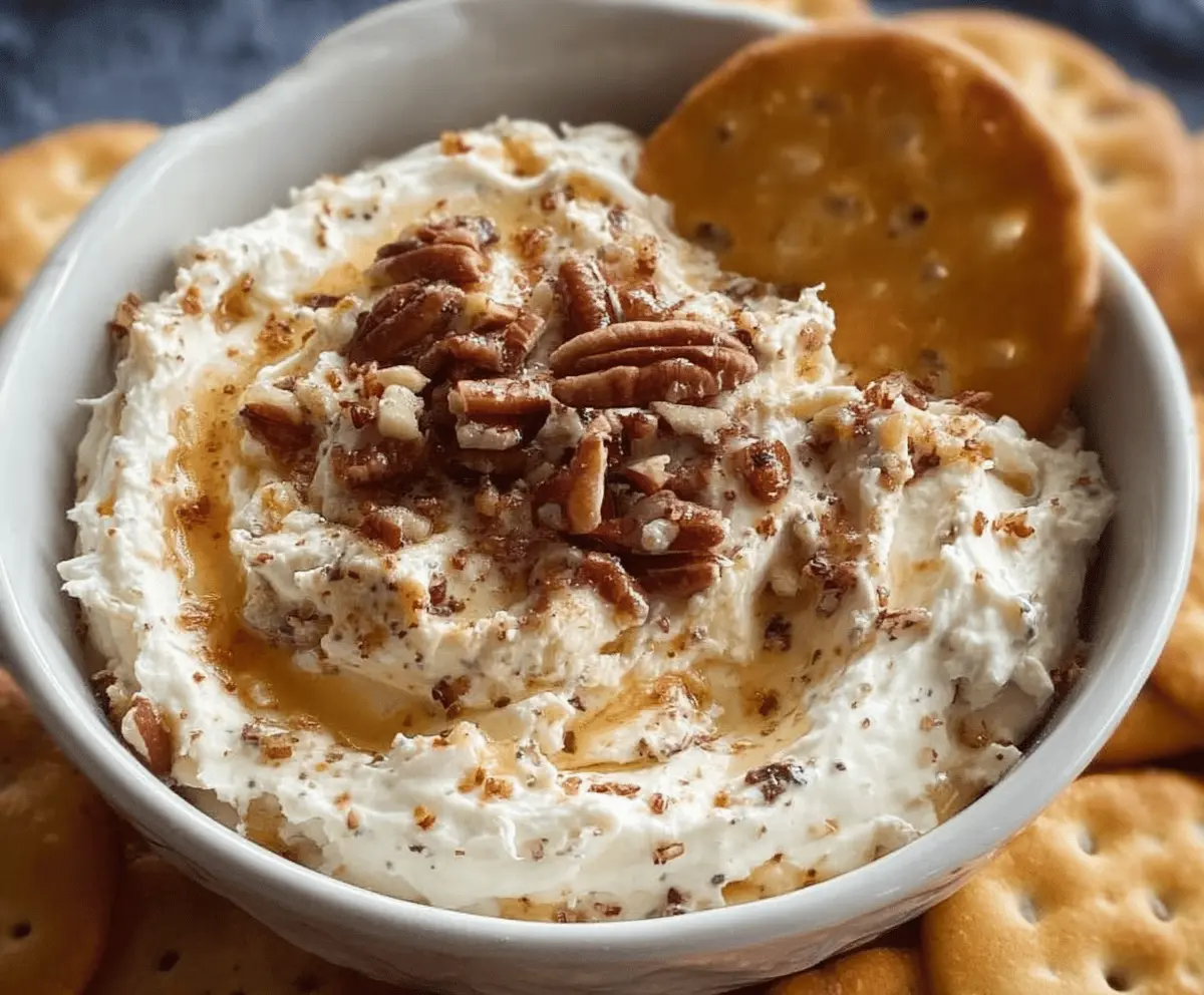 Creamy whipped Parmesan and honey pecan cheese dip garnished with pecans and fresh herbs, perfect for serving as an appetizer or party snack.