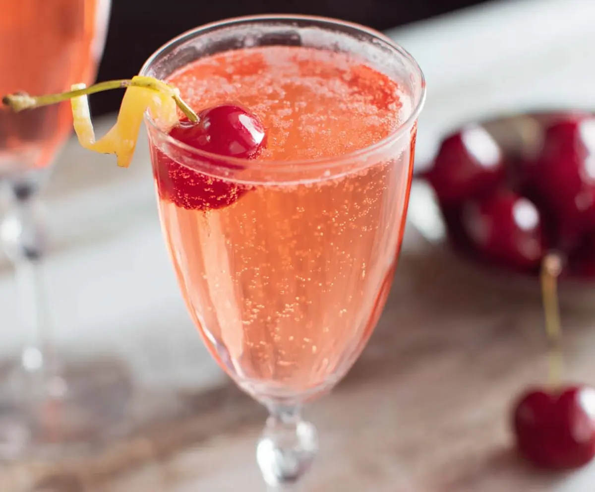 Elegant Pink Champagne Cocktail in a flute glass garnished with a cherry for a festive look.