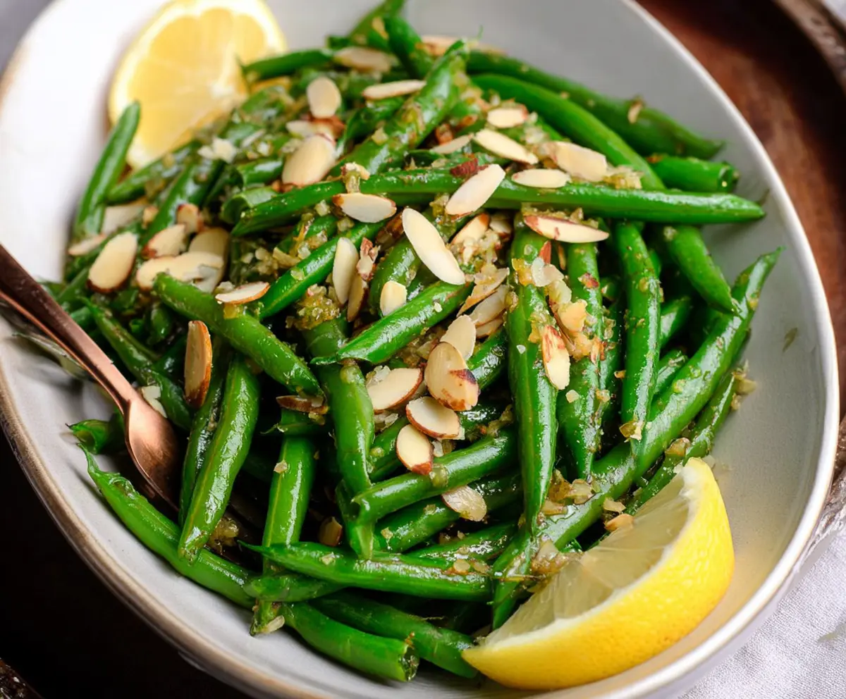 Fresh green bean almondine dish featuring tender green beans topped with toasted almonds and a squeeze of lemon.